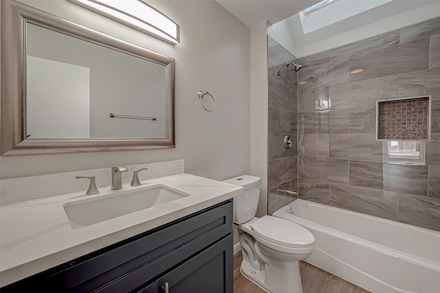 full bathroom with a skylight, hardwood / wood-style floors, toilet, vanity, and tiled shower / bath combo