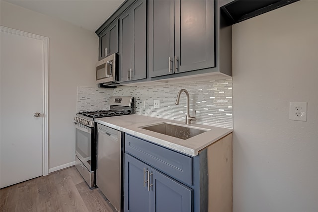 kitchen featuring appliances with stainless steel finishes, light hardwood / wood-style flooring, tasteful backsplash, and sink