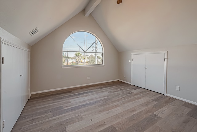 unfurnished bedroom with lofted ceiling with beams and light hardwood / wood-style flooring