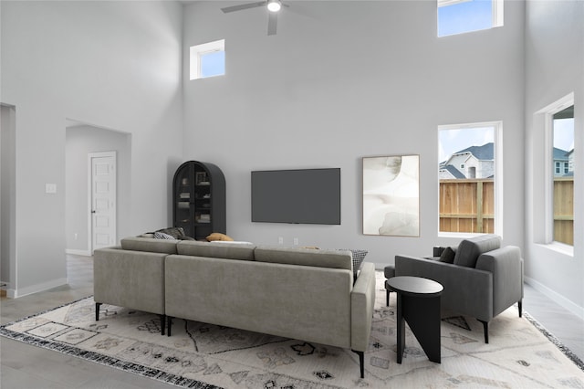 living room featuring a wealth of natural light, ceiling fan, and a towering ceiling