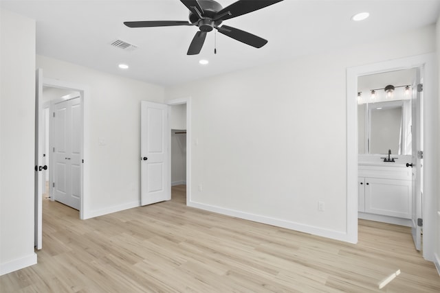 unfurnished bedroom with light wood-type flooring, connected bathroom, ceiling fan, and sink