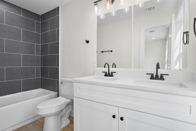 full bathroom with vanity, hardwood / wood-style floors, tiled shower / bath combo, and toilet