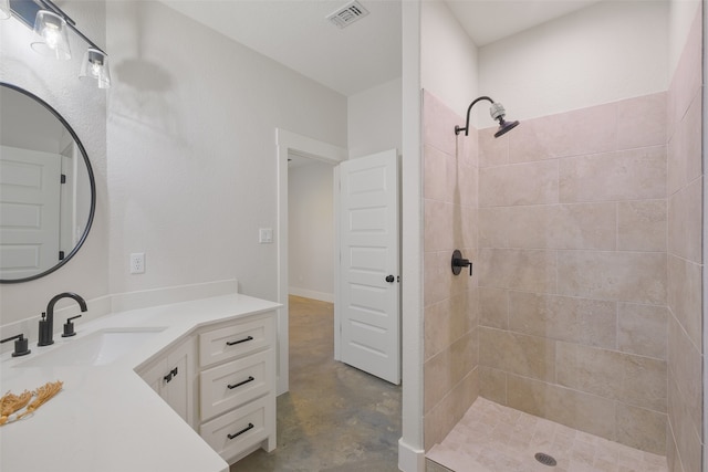 bathroom with concrete flooring, vanity, and tiled shower