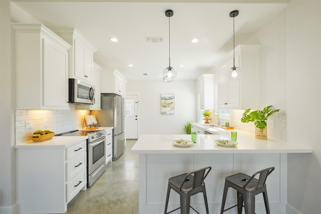 kitchen featuring sink, appliances with stainless steel finishes, hanging light fixtures, white cabinets, and kitchen peninsula