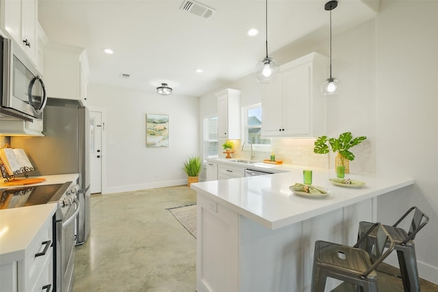 kitchen with white cabinetry, stainless steel appliances, kitchen peninsula, decorative light fixtures, and a breakfast bar