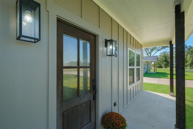 view of exterior entry with a porch and a lawn