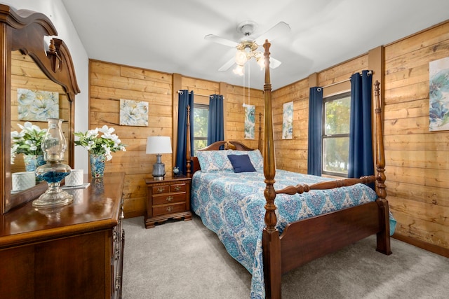 bedroom featuring wood walls, ceiling fan, and light carpet