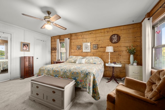 bedroom with light carpet, ceiling fan, and wood walls