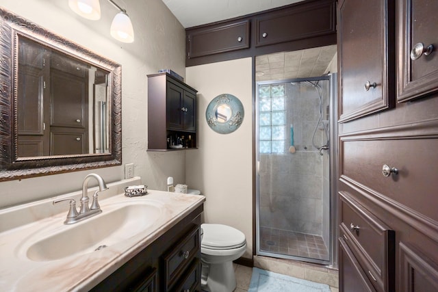 bathroom featuring toilet, an enclosed shower, vanity, and tile patterned floors