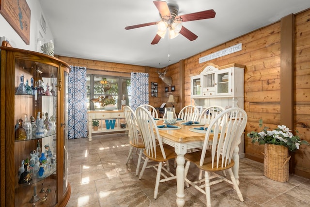 dining room featuring ceiling fan and wooden walls