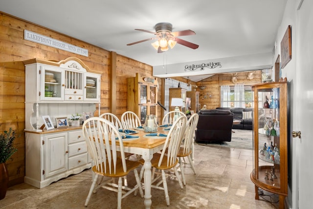 dining space with wood walls and ceiling fan