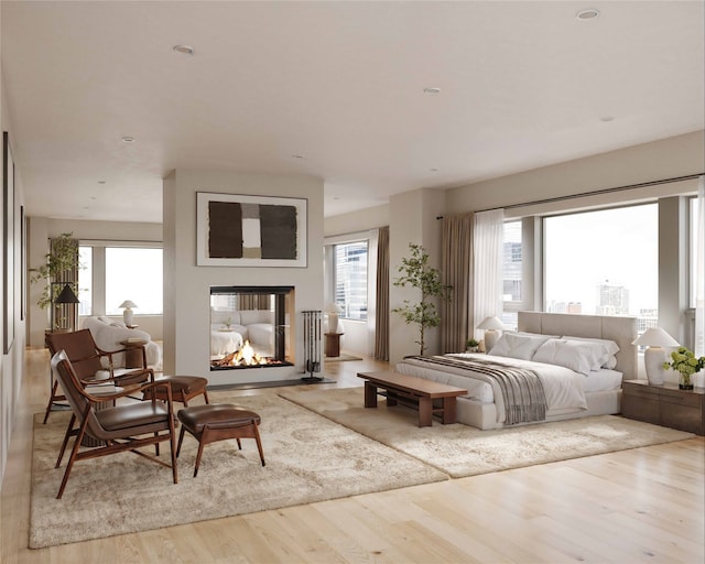 bedroom with a multi sided fireplace and light wood-type flooring