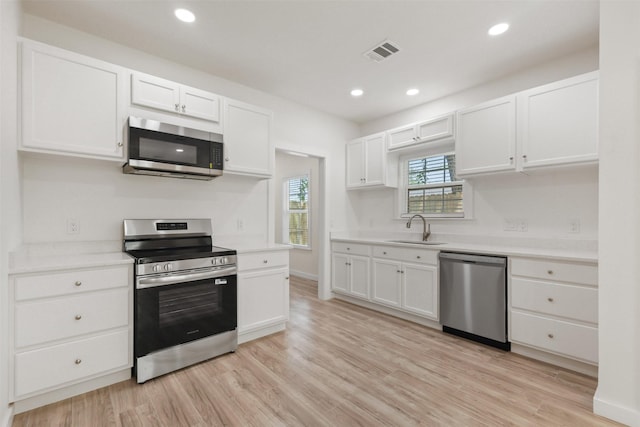 1310 E Alamo St A-B, Unit A-B Brenham, TX 77833 - kitchen with light wood-type flooring, white cabinets, visible vents, a sink, and stainless steel appliances