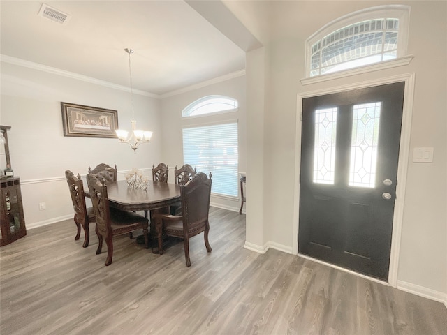 dining room featuring a notable chandelier, hardwood / wood-style flooring, crown molding, and plenty of natural light