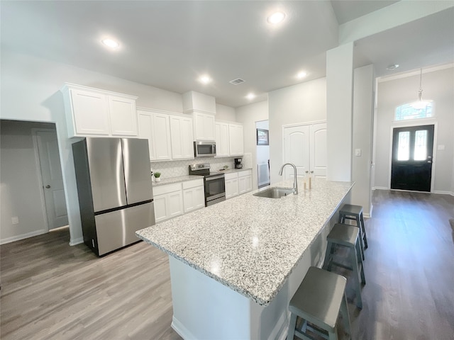 kitchen with light hardwood / wood-style flooring, appliances with stainless steel finishes, sink, and white cabinetry