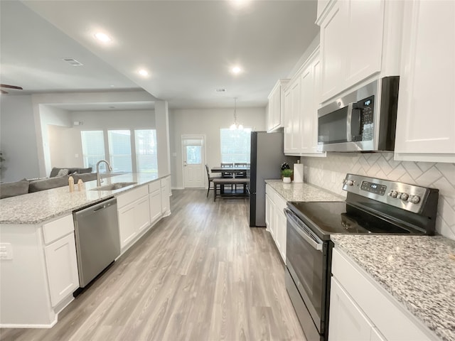 kitchen with light hardwood / wood-style floors, stainless steel appliances, sink, and white cabinetry