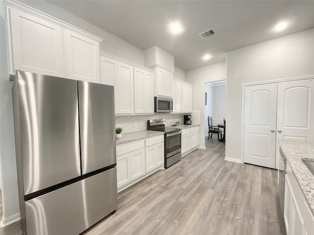 kitchen with light stone countertops, appliances with stainless steel finishes, and white cabinetry