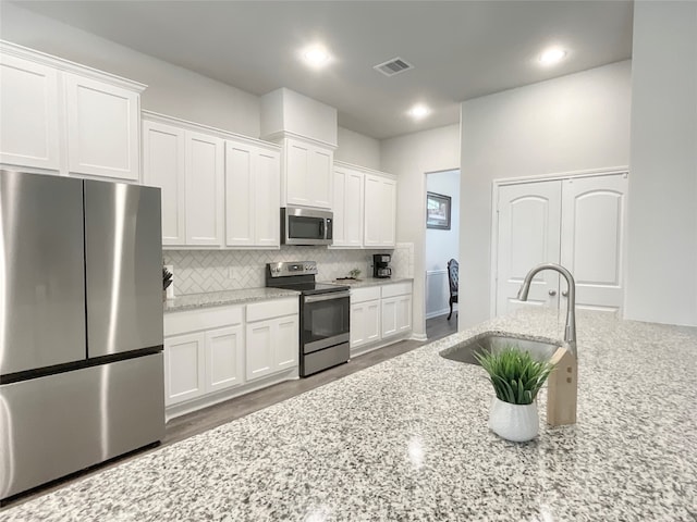 kitchen featuring light stone counters, stainless steel appliances, dark wood-type flooring, and white cabinetry