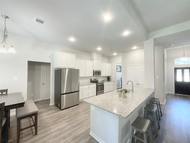 kitchen featuring light hardwood / wood-style flooring, a center island with sink, sink, appliances with stainless steel finishes, and white cabinetry