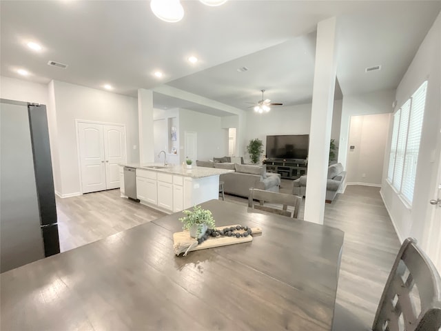 dining area with ceiling fan, sink, and light hardwood / wood-style flooring