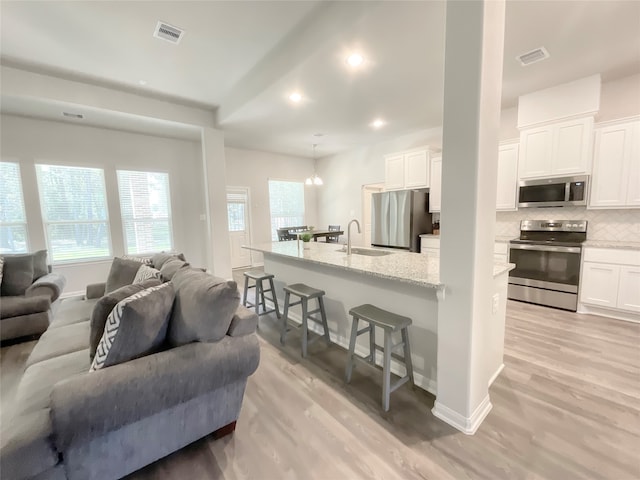 living room featuring an inviting chandelier, sink, and light hardwood / wood-style floors