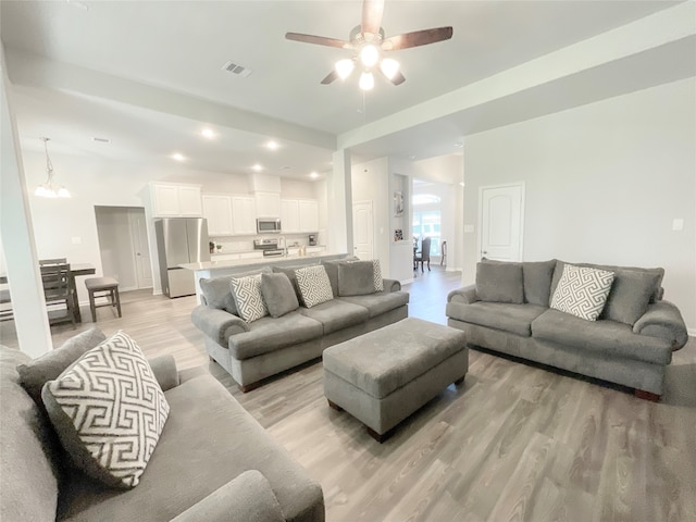 living room with ceiling fan with notable chandelier and light hardwood / wood-style floors