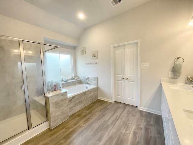 bathroom with independent shower and bath, vanity, vaulted ceiling, and wood-type flooring