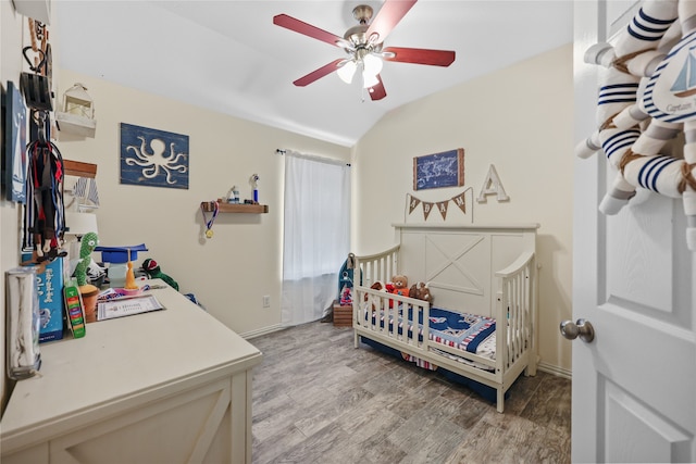 bedroom with lofted ceiling, a nursery area, light hardwood / wood-style flooring, and ceiling fan