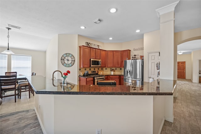 kitchen featuring appliances with stainless steel finishes, light hardwood / wood-style flooring, and kitchen peninsula