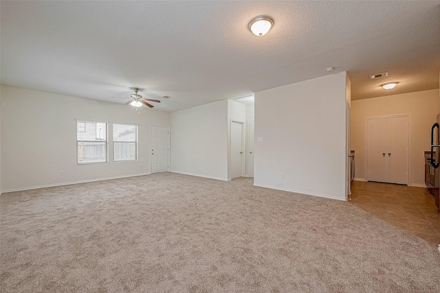 spare room with light carpet, ceiling fan, and a textured ceiling