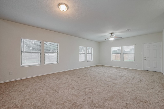 spare room featuring ceiling fan, light colored carpet, and a textured ceiling