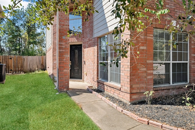 view of exterior entry featuring central AC unit and a lawn