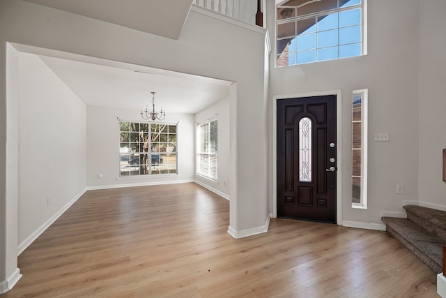 foyer entrance featuring a high ceiling, an inviting chandelier, and light hardwood / wood-style floors