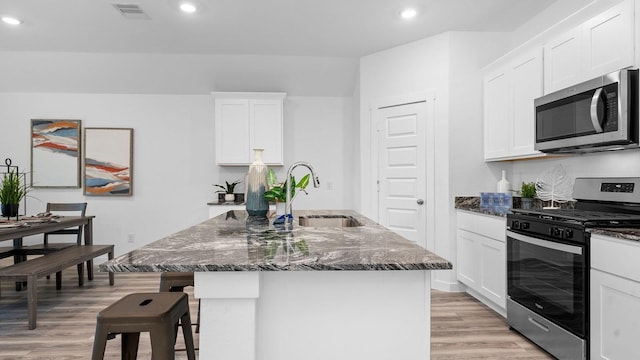 kitchen featuring a kitchen island with sink, white cabinetry, sink, and appliances with stainless steel finishes