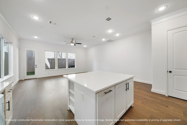 kitchen featuring ceiling fan, a center island, white cabinets, dark hardwood / wood-style flooring, and ornamental molding