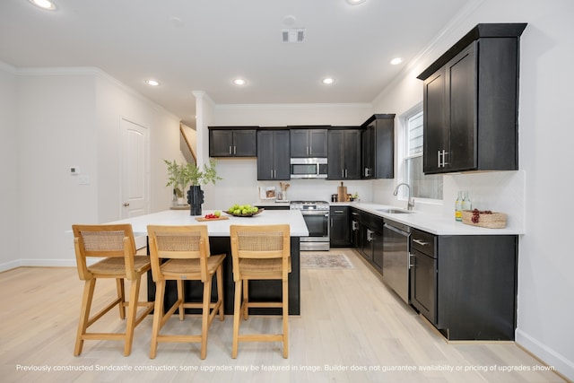 kitchen featuring light wood-type flooring, a breakfast bar area, sink, appliances with stainless steel finishes, and a center island