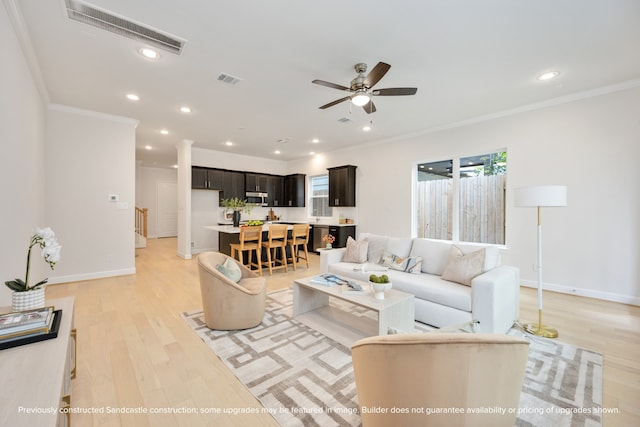 living room featuring ceiling fan, light wood-type flooring, and ornamental molding