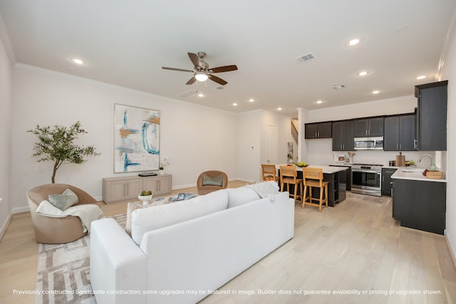 living room with sink, ornamental molding, light hardwood / wood-style flooring, and ceiling fan