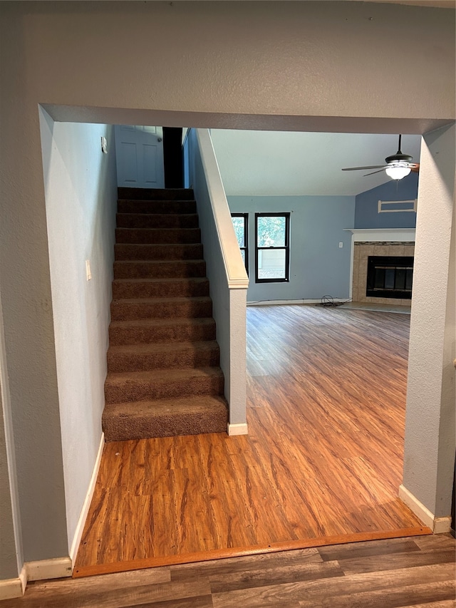 stairs featuring a tiled fireplace and hardwood / wood-style floors