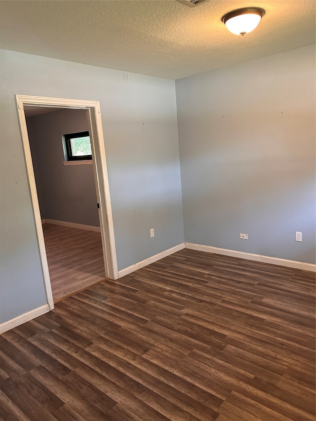 unfurnished room with a textured ceiling and dark hardwood / wood-style flooring