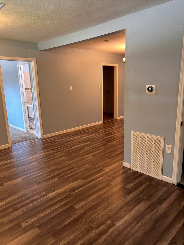 spare room featuring dark hardwood / wood-style floors and a textured ceiling