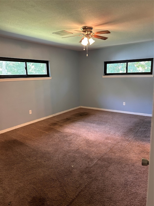 carpeted spare room with ceiling fan, a textured ceiling, and a healthy amount of sunlight