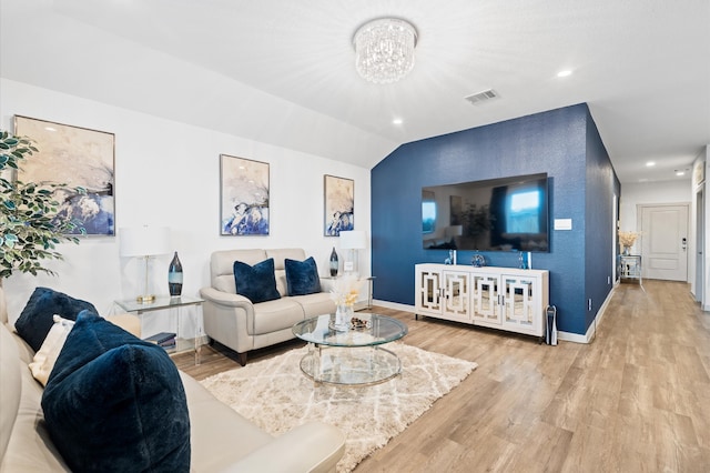 living room featuring a notable chandelier, vaulted ceiling, and light hardwood / wood-style floors