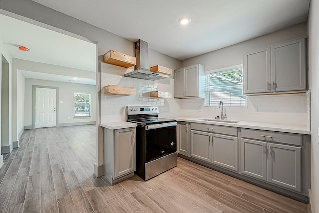 kitchen with wall chimney range hood, gray cabinets, a wealth of natural light, and stainless steel electric range