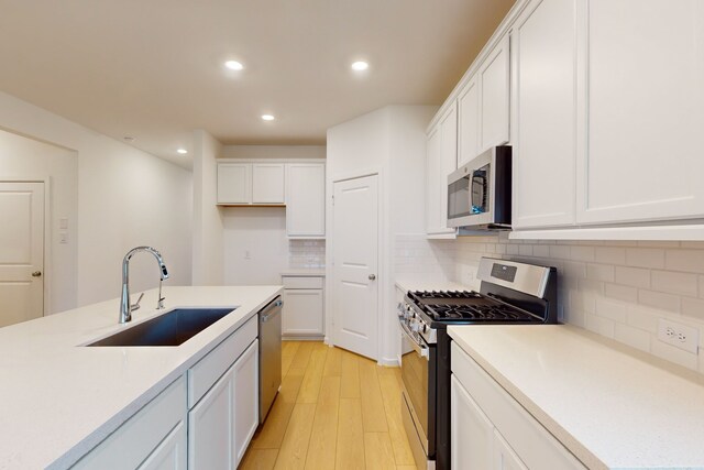 kitchen featuring white cabinetry, appliances with stainless steel finishes, sink, and light wood-type flooring