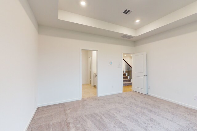 carpeted empty room with a raised ceiling