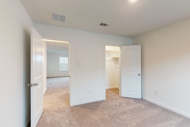 unfurnished bedroom featuring light carpet, a closet, and a spacious closet