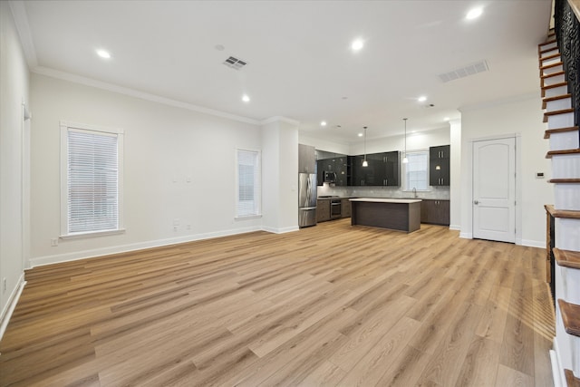 unfurnished living room featuring ornamental molding, light wood-type flooring, and sink