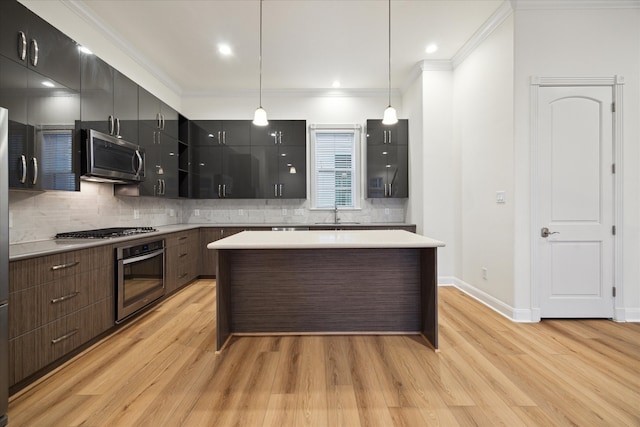 kitchen featuring pendant lighting, stainless steel appliances, ornamental molding, and light hardwood / wood-style floors