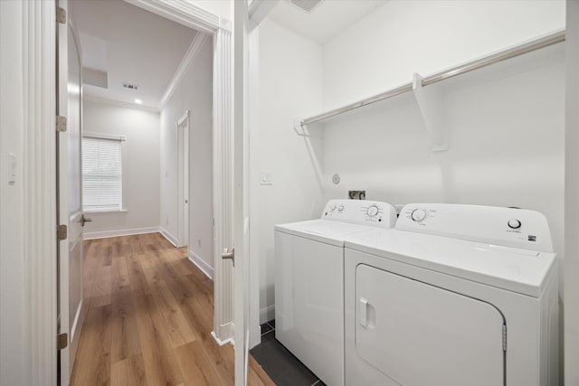 washroom featuring independent washer and dryer, ornamental molding, and light hardwood / wood-style flooring